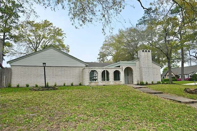 view of front of house featuring brick siding, a chimney, and a front lawn