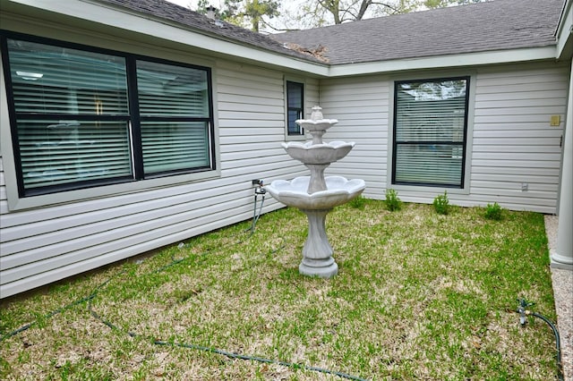 exterior space featuring a lawn and roof with shingles