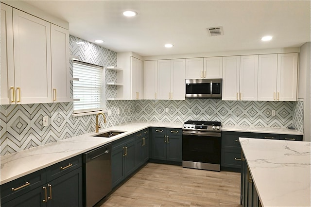 kitchen with a sink, stainless steel appliances, visible vents, and white cabinetry