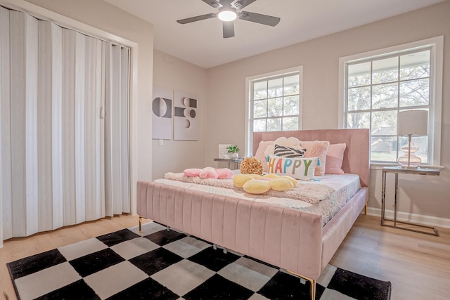 bedroom with multiple windows, a ceiling fan, light wood-style flooring, and baseboards