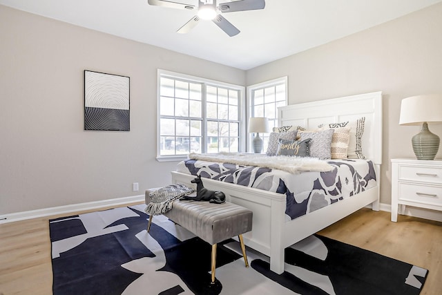 bedroom with multiple windows, wood finished floors, and baseboards