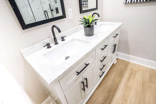 bathroom featuring a sink, baseboards, wood finished floors, and double vanity