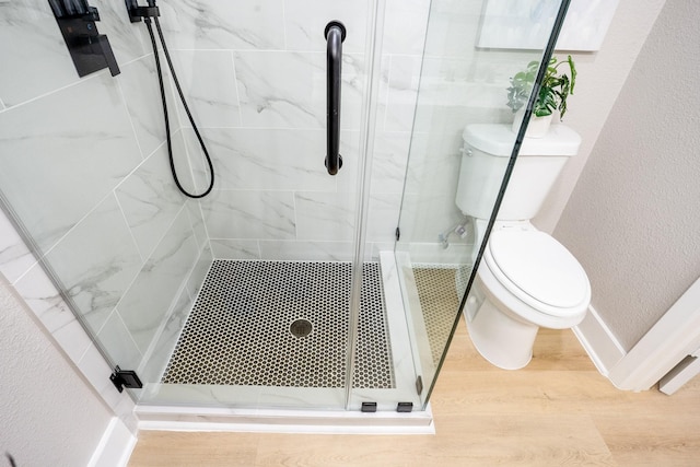 full bathroom featuring wood finished floors, baseboards, a stall shower, toilet, and a textured wall