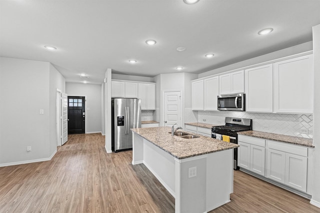 10718 Soapberry Ct, Tomball, TX 77375 - kitchen with appliances with stainless steel finishes, a sink, light wood-style flooring, white cabinetry, and decorative backsplash