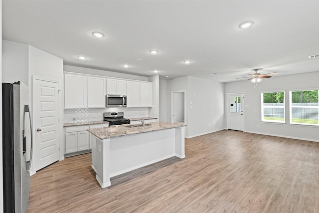 10718 Soapberry Ct, Tomball, TX 77375 - kitchen featuring a sink, light wood-style flooring, stainless steel appliances, white cabinetry, and decorative backsplash