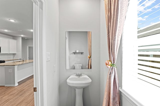 10718 Soapberry Ct, Tomball, TX 77375 - bathroom featuring backsplash, wood finished floors, a sink, baseboards, and recessed lighting