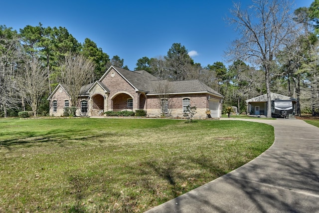 view of front facade featuring brick siding, a garage, driveway, and a front lawn