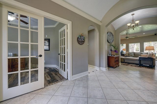 interior space featuring light tile patterned floors, baseboards, arched walkways, vaulted ceiling, and ceiling fan with notable chandelier