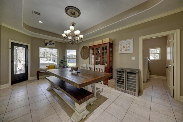 dining room featuring a tray ceiling, a notable chandelier, light tile patterned flooring, and washer and clothes dryer