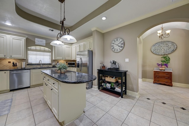 kitchen featuring a sink, tasteful backsplash, stainless steel appliances, arched walkways, and a raised ceiling