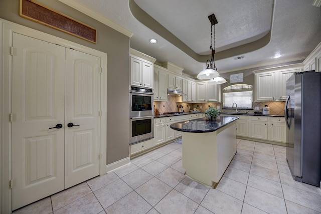 kitchen featuring light tile patterned floors, a raised ceiling, a kitchen island, and appliances with stainless steel finishes