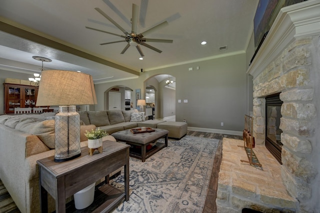 living room featuring visible vents, baseboards, arched walkways, ornamental molding, and ceiling fan with notable chandelier