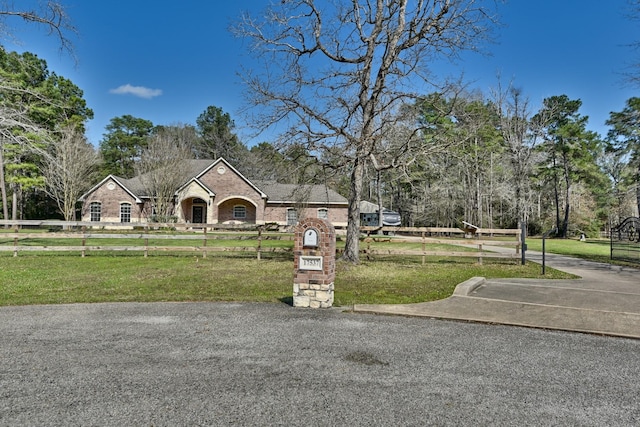 view of front facade featuring a front lawn, fence, and brick siding