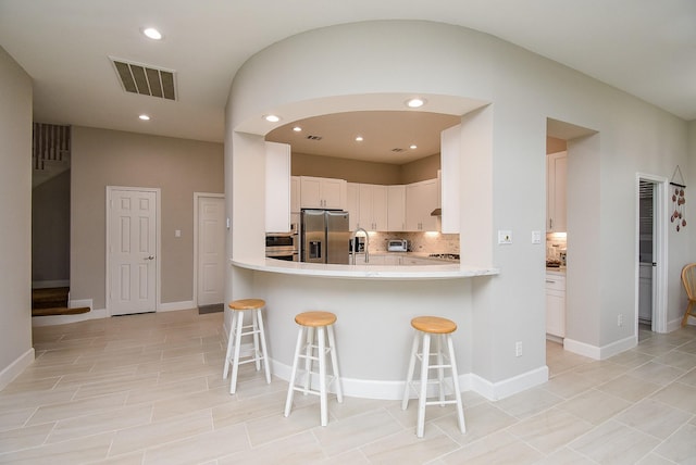 3211 Riviera Dr, Sugar Land, TX 77479 - kitchen with visible vents, stainless steel fridge with ice dispenser, decorative backsplash, light countertops, and a kitchen bar