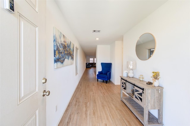 corridor featuring visible vents, baseboards, and light wood-style floors