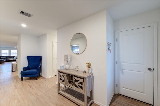 hall featuring light wood finished floors, visible vents, and baseboards