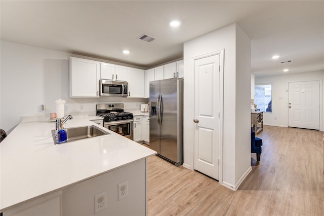 kitchen featuring visible vents, a sink, stainless steel appliances, light countertops, and light wood-type flooring