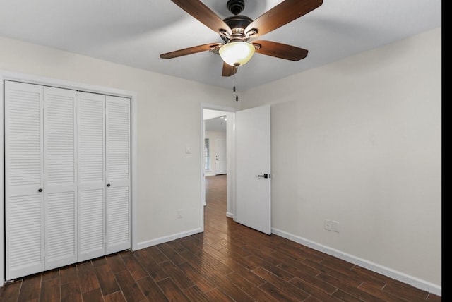 unfurnished bedroom featuring a closet, baseboards, dark wood-style floors, and a ceiling fan