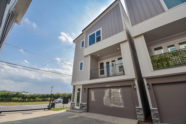 view of home's exterior featuring stone siding, a balcony, board and batten siding, and a garage