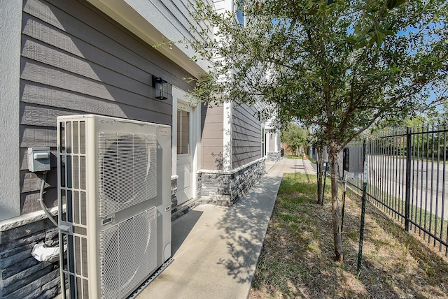 view of side of property with ac unit, stone siding, and fence