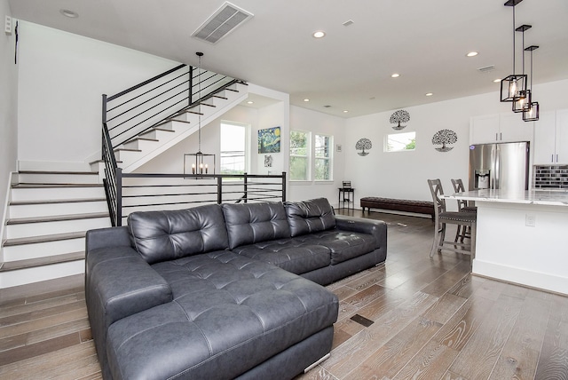 living area with visible vents, stairs, recessed lighting, wood finished floors, and a notable chandelier