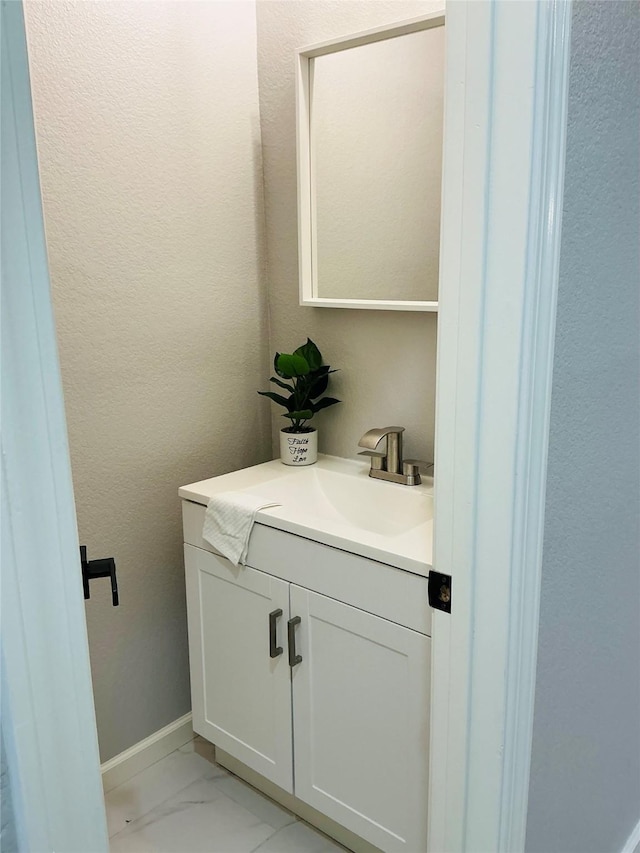 bathroom with vanity, a textured wall, marble finish floor, and baseboards