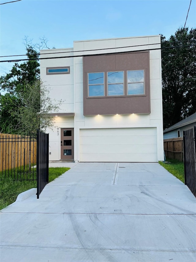 contemporary house featuring a garage, fence, driveway, and stucco siding