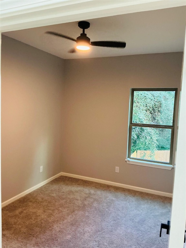 carpeted spare room featuring baseboards and ceiling fan