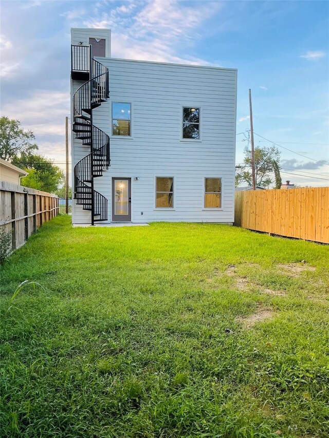 back of house with stairs, fence, and a lawn