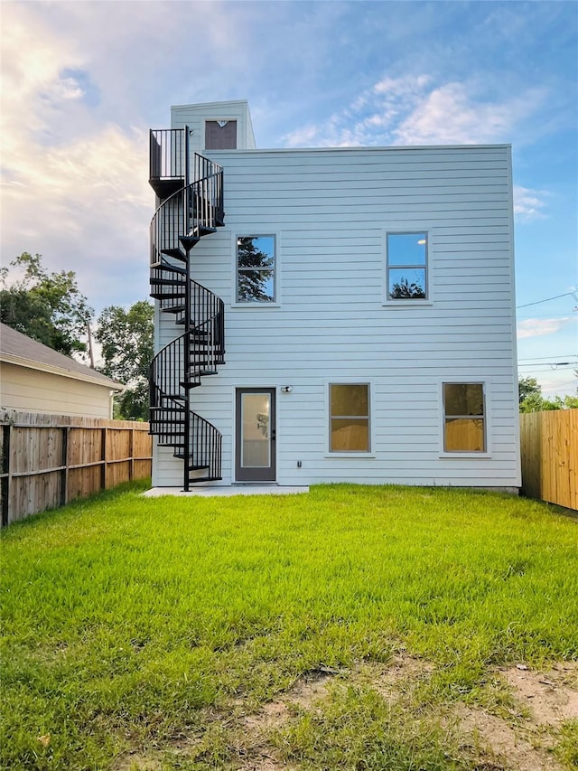 rear view of house featuring a yard, stairs, and fence