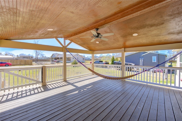 wooden terrace with a residential view, ceiling fan, and a yard