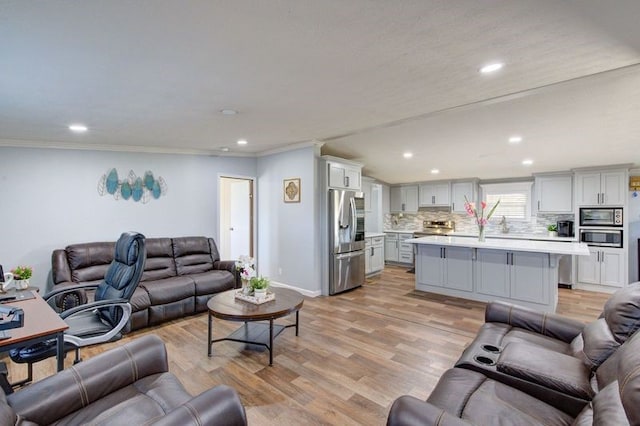 living area with recessed lighting, light wood-type flooring, baseboards, and crown molding