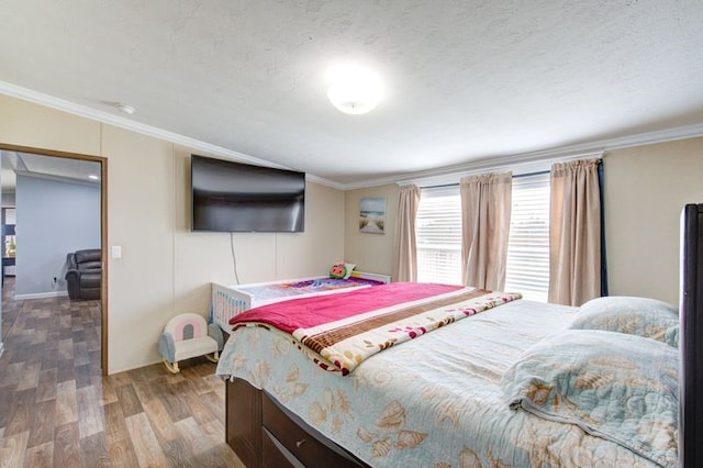 bedroom with a textured ceiling, wood finished floors, and ornamental molding