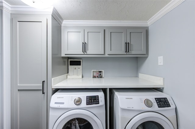 clothes washing area with washer and dryer, crown molding, cabinet space, and a textured ceiling