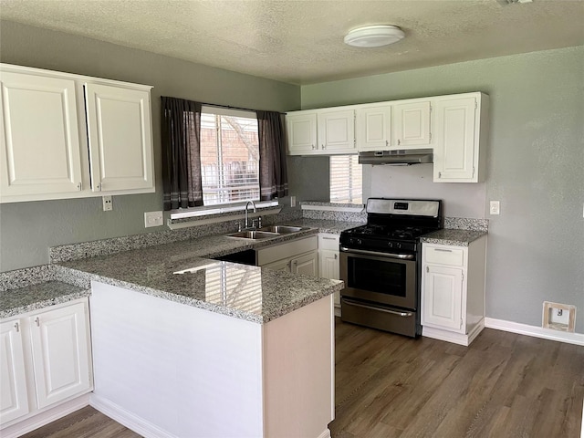 kitchen featuring a peninsula, a sink, white cabinets, under cabinet range hood, and stainless steel gas stove