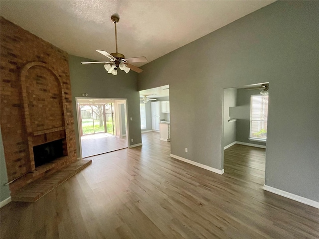 unfurnished living room with a fireplace, wood finished floors, a wealth of natural light, and ceiling fan