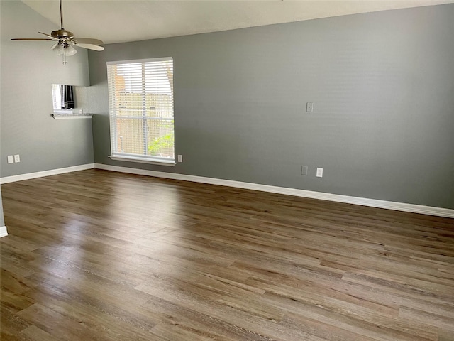 spare room with baseboards, wood finished floors, and a ceiling fan