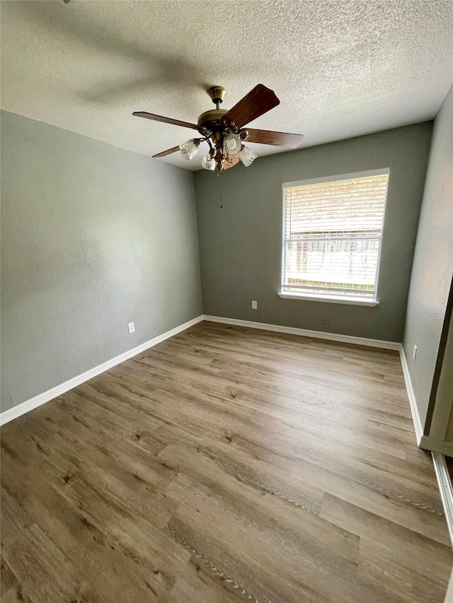 spare room featuring a textured ceiling, baseboards, a ceiling fan, and wood finished floors