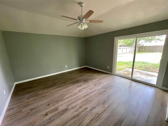 unfurnished room with ceiling fan, baseboards, wood finished floors, and vaulted ceiling