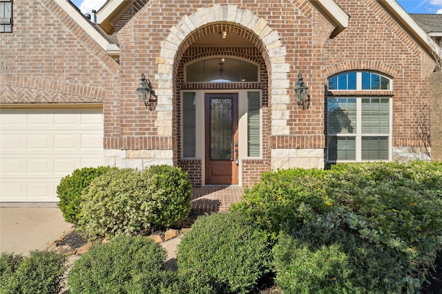 view of exterior entry with brick siding, stone siding, and an attached garage