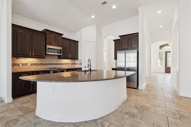 kitchen featuring visible vents, arched walkways, a sink, appliances with stainless steel finishes, and backsplash