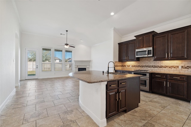 kitchen featuring decorative backsplash, appliances with stainless steel finishes, dark stone counters, and a sink