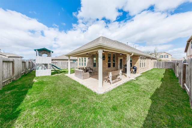 back of house with brick siding, a patio area, a playground, and a fenced backyard