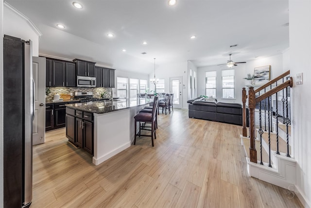 kitchen featuring a kitchen island, a kitchen breakfast bar, stainless steel appliances, and light wood-type flooring