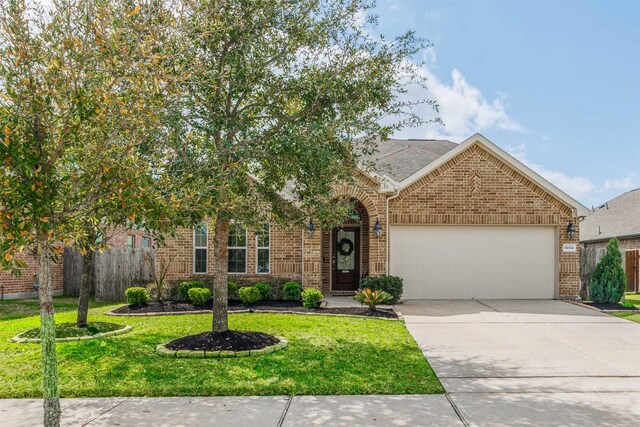 view of front facade featuring concrete driveway, fence, brick siding, and a front yard