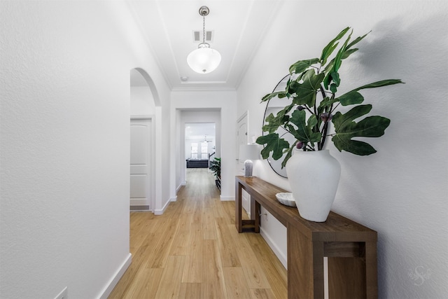 corridor featuring arched walkways, visible vents, light wood-style flooring, and baseboards