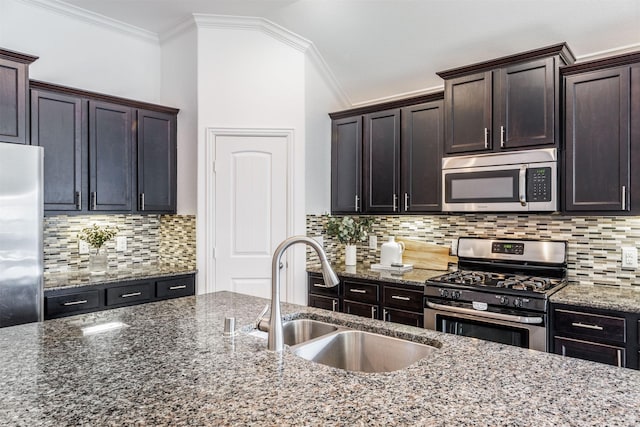 kitchen with a sink, stainless steel appliances, backsplash, and dark stone countertops