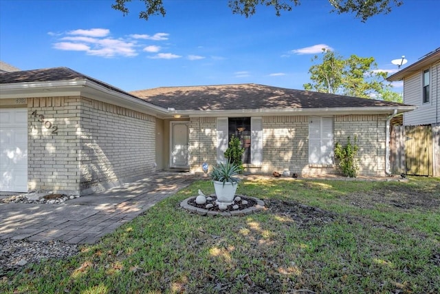 view of front of home featuring brick siding, an attached garage, a front yard, and fence