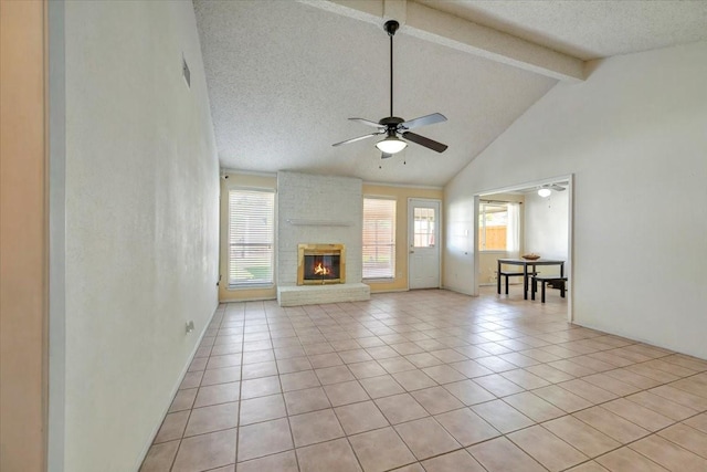 unfurnished living room featuring light tile patterned floors, beamed ceiling, ceiling fan, a textured ceiling, and a brick fireplace