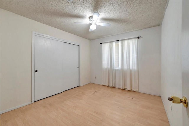 unfurnished bedroom featuring a closet, light wood-style flooring, a textured ceiling, and a ceiling fan